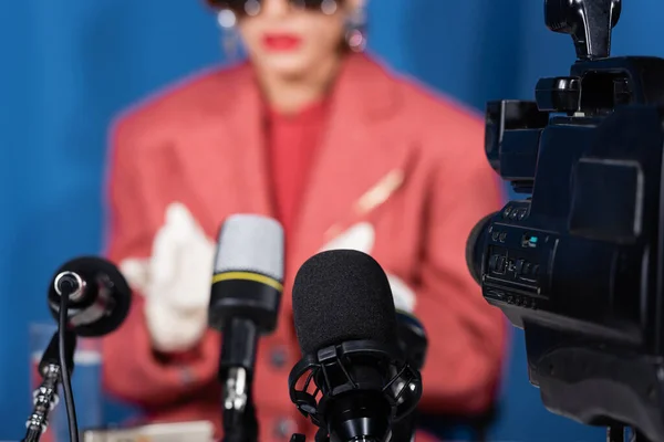 Nahaufnahme von Mikrofonen und Videokamera in der Nähe einer abgeschnittenen Frau, die ein Interview auf verschwommenem Hintergrund gibt — Stockfoto