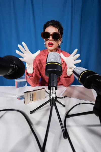 Joven vintage estilo mujer gesto durante la entrevista sobre fondo azul - foto de stock