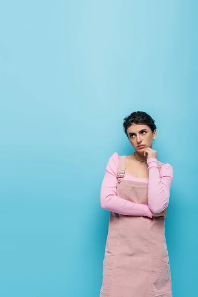 Mujer frustrada sosteniendo la mano cerca de la cara mientras mira hacia otro lado aislado en azul - foto de stock