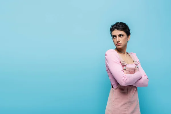 Offended woman standing with crossed arms and looking back isolated on blue — Stock Photo