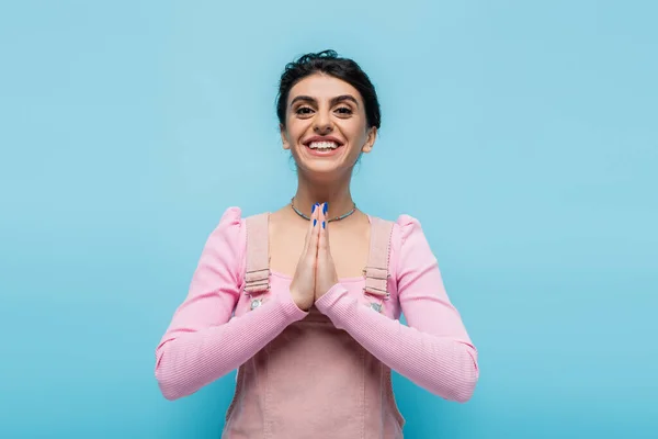 Joven morena mostrando gesto de gratitud y sonriendo a la cámara aislada en azul - foto de stock