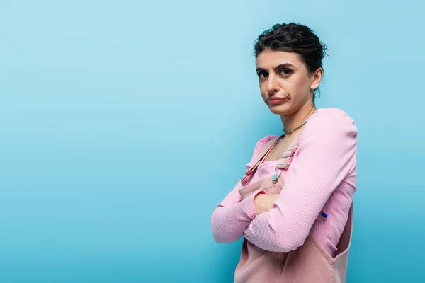 Offended woman standing with crossed arms while looking at camera isolated on blue — Stock Photo