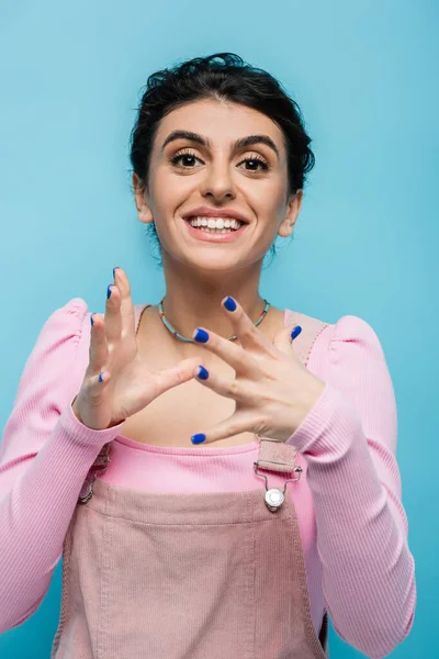 Delighted woman showing wow gesture and looking at camera isolated on blue — Stock Photo