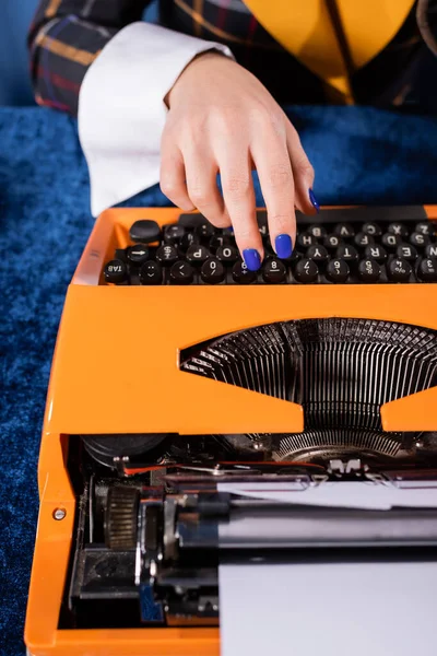 Partial view of journalist typing on vintage typewriter on blue velour tablecloth — Stock Photo