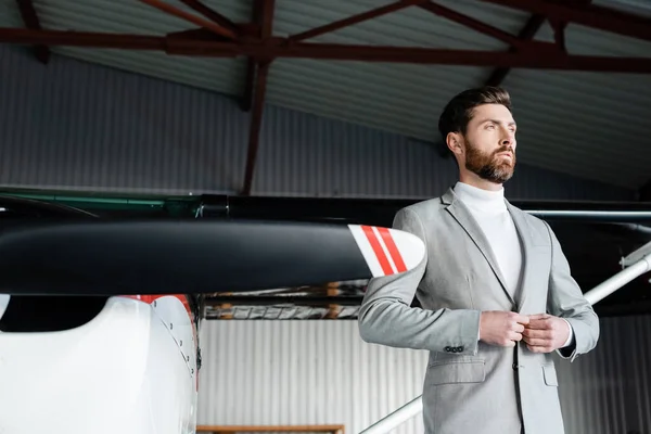 Bearded man in suit buttoning blazer near helicopter — Stock Photo