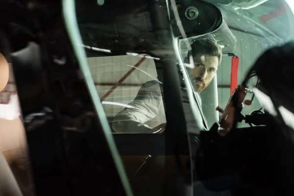 Bearded man looking at camera through modern helicopter windscreen — Stock Photo