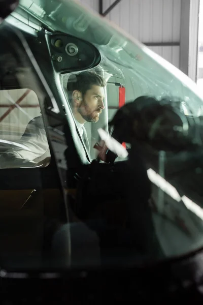 Uomo barbuto guardando lontano vicino elicottero moderno attraverso il parabrezza — Foto stock