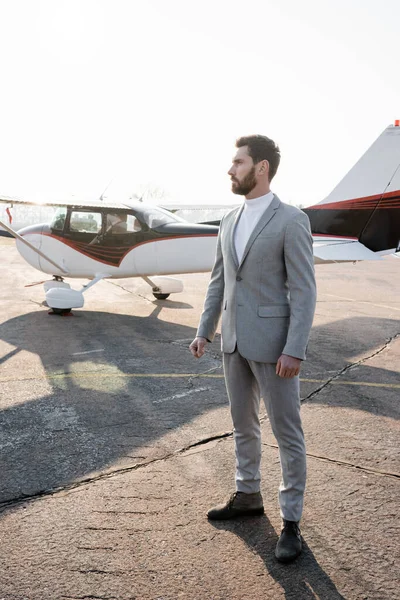 Full length of serious businessman in suit standing near helicopter outdoors — Stock Photo