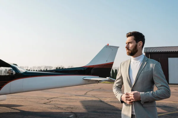 Serious businessman in suit standing near helicopter on outdoor parking — Stock Photo