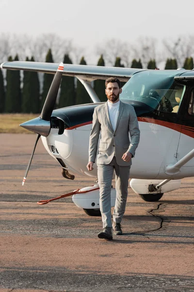 Homme d'affaires barbu marchant sur toute la longueur près de l'hélicoptère à l'extérieur — Photo de stock