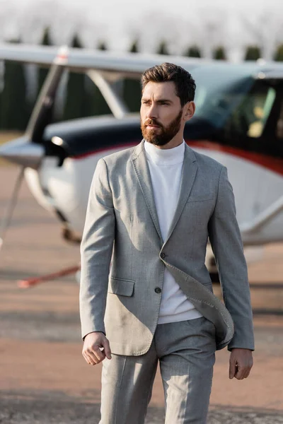 Hombre de negocios barbudo caminando cerca de helicóptero borroso al aire libre — Stock Photo