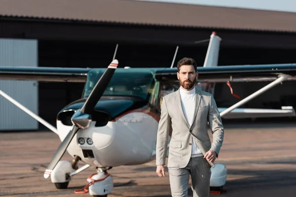 Homem de negócios bonito em terno andando perto de helicóptero moderno ao ar livre — Fotografia de Stock