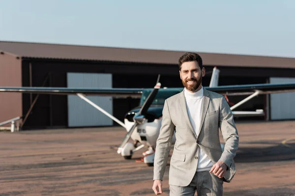 Alegre hombre de negocios en traje caminando cerca de helicóptero moderno al aire libre - foto de stock