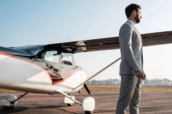 Vista laterale di uomo d'affari di successo in giacca e cravatta in piedi vicino elicottero all'aperto — Foto stock