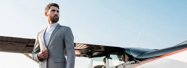 Vista basso angolo di uomo d'affari di successo in giacca e cravatta in piedi vicino elicottero all'aperto, banner — Foto stock