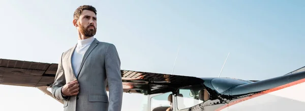 Low angle view of successful businessman in suit standing near helicopter outdoors, banner — Stock Photo