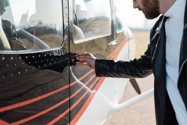 Vue recadrée du pilote barbu ouvrant la porte de l'hélicoptère — Photo de stock