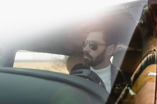 View of bearded pilot in stylish sunglasses inside of in cockpit through helicopter windscreen — Stock Photo