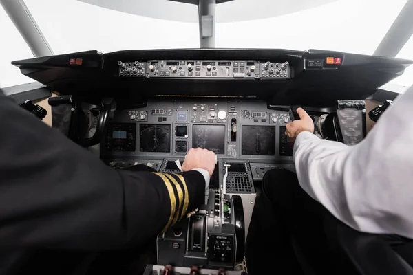 Cropped view of pilots using yoke and thrust lever in airplane simulator — Stock Photo