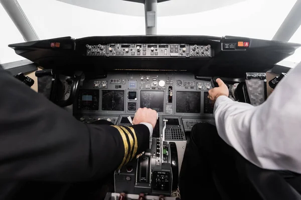 Vue recadrée des pilotes utilisant le levier de serrage et de poussée dans le simulateur d'avion — Photo de stock