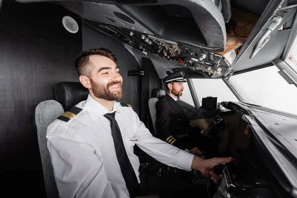 Smiling co-pilot using yoke near captain while piloting in airplane simulator — Stock Photo