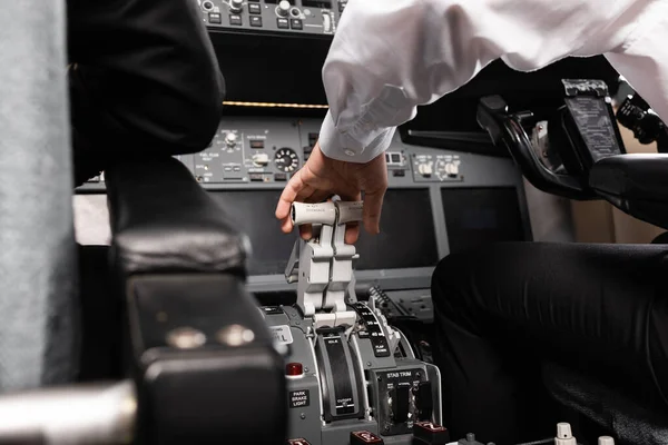 Vista recortada del copiloto utilizando palanca de empuje en simulador de avión - foto de stock