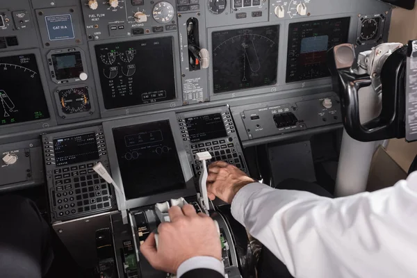 Vista ad alto angolo del pilota che utilizza la leva di spinta vicino al copilota nel simulatore di aeroplano — Foto stock