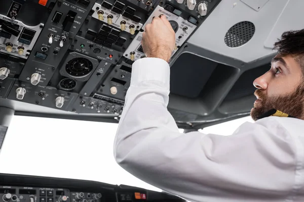 Bearded pilot pressing button on overhead panel in airplane simulator — Stock Photo