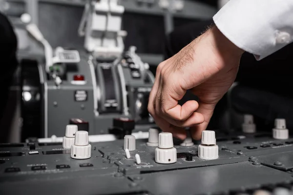 Cropped view of pilot using switcher on control panel in airplane — Stock Photo