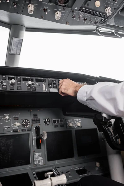 Vista recortada del piloto que alcanza el panel de control en el avión - foto de stock