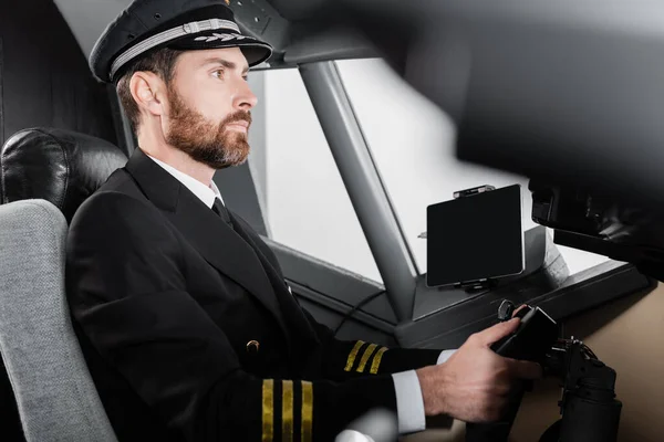 Side view of bearded pilot in uniform using yoke in airplane — Stock Photo