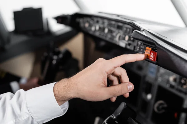 Vista recortada del piloto pulsando el botón principal de precaución en el simulador de avión - foto de stock
