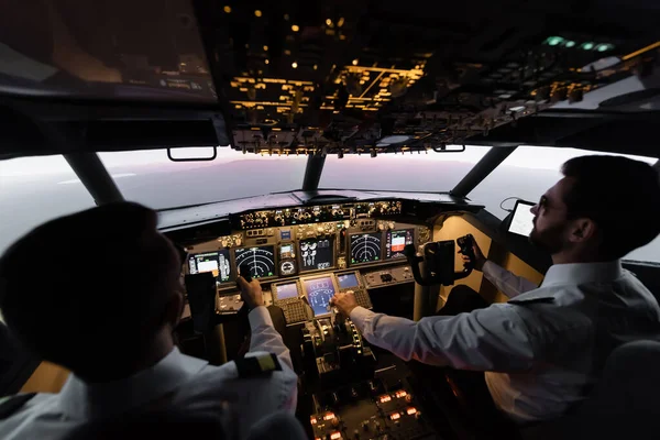 Vista de ángulo alto de los profesionales que pilotan el avión en la noche durante la puesta del sol - foto de stock