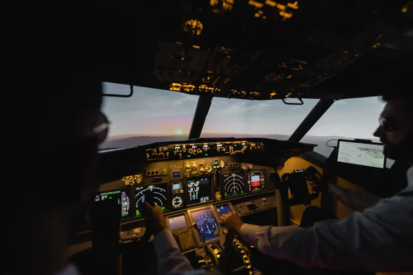 Profesionales desdibujados piloteando el avión en la noche durante la puesta del sol - foto de stock