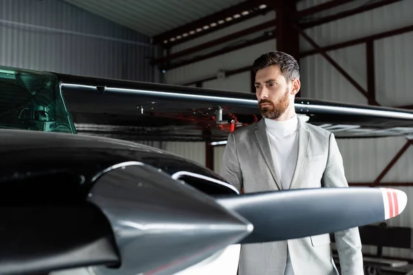 Bearded man in grey suit looking at modern helicopter — Stock Photo