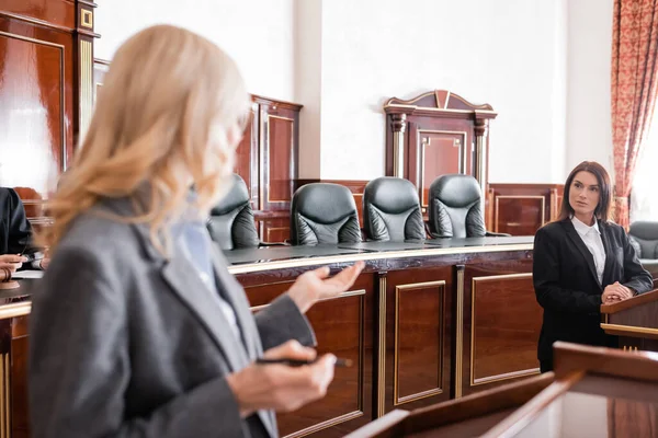 Blurred attorney pointing with hand and talking to witness during litigation — Stock Photo