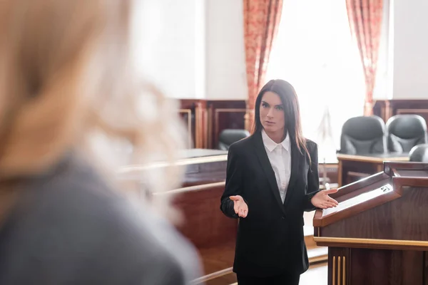 Fiscal señalando con las manos mientras habla con testigo borroso en la sala del tribunal - foto de stock