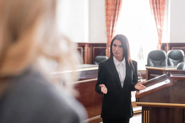 Prosecutor pointing with hands while talking to blurred witness in courtroom — Stock Photo