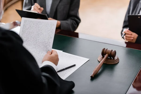 Partial view of judge holding lawsuit near advocate and prosecutor with clipboards — Stock Photo