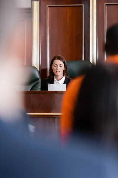 Prosecutor reading lawsuit near accused african american man and jurors on blurred background — Stock Photo