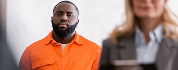 African american man in jail uniform near advocate on blurred foreground, banner — Stock Photo