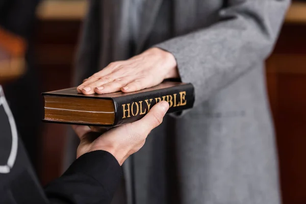 Partial view of bailiff holding bible near woman giving swear in court — Stock Photo
