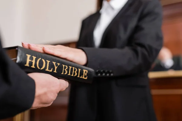 Vista ritagliata della donna offuscata che dà giuramento sulla Bibbia durante il contenzioso — Foto stock