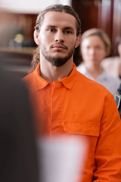 Selective focus of bearded man in orange jail uniform standing in courtroom — Stock Photo