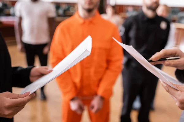 Partial view of advocate and prosecutor with documents near accused man and jurors on blurred background — Stock Photo