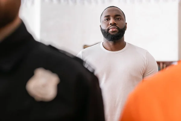 African american juryman standing near accused man and bailiff on blurred foreground — Stock Photo