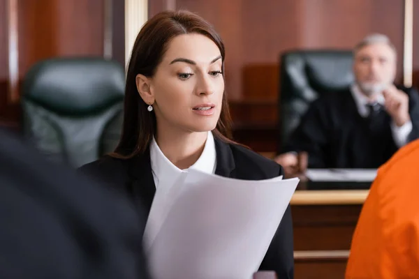 Morena fiscal leyendo demanda en el tribunal en primer plano borrosa - foto de stock