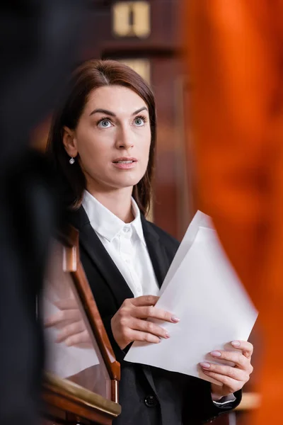 Brunette lawyer holding documents in courtroom on blurred foreground — Stock Photo