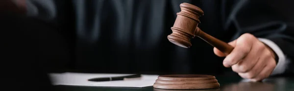 Partial view of blurred judge holding gavel during sentencing, banner — Stock Photo