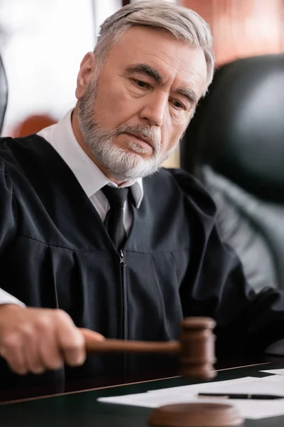 Senior judge with blurred gavel sentencing in court — Stock Photo